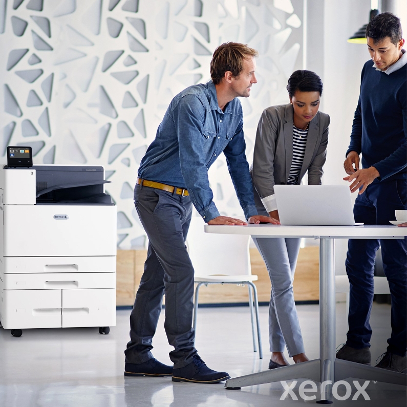Employés de bureau en réunion avec une imprimante Xerox.